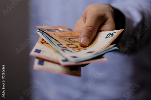 A hand holding Euro banknot...