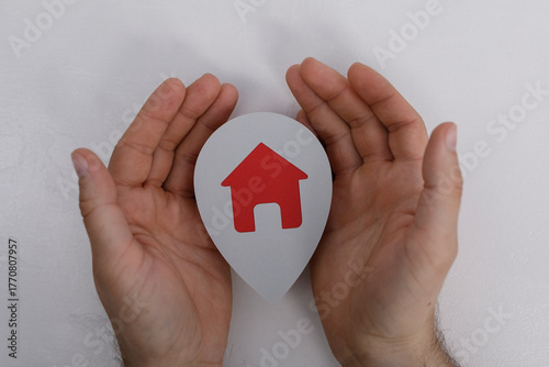 Hands cupping a red house i...