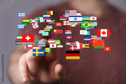 A human hand connects with numerous world flags, symbolizing global unity, international relations, and communication. Visual metaphor for world