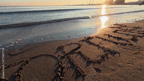 The word “FORTUNE” written on the sand near the shoreline, with gentle sea waves approaching.
