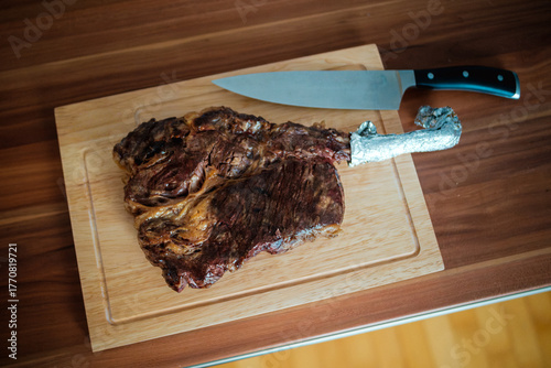 Tomahawk Steak mit Messer auf Holzbrett