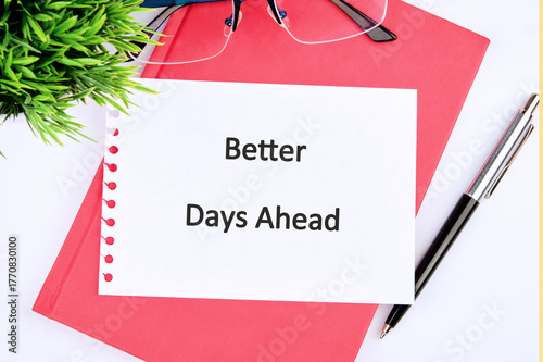 A notepad with a motivational note stating better days ahead sits on a clean surface. Nearby, a pair of glasses and a black pen offer a sense of focus and inspiration for the day