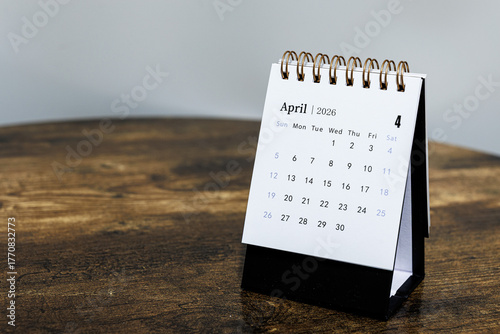 April 2026 monthly calendar page on a wooden desk, minimal design planner representing time management and organization at workplace