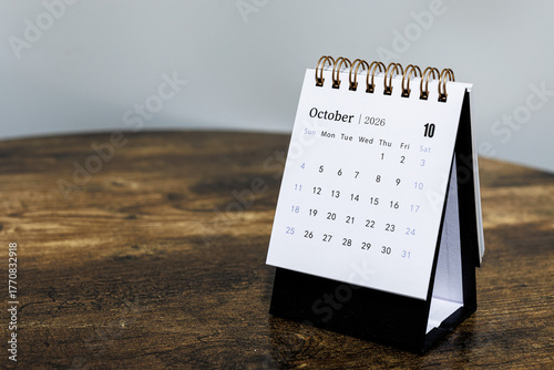 October 2026 monthly calendar page on a wooden desk, minimal design planner representing time management and organization at workplace