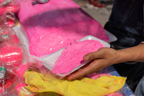Fotografia Turrón Candy, Close up of a man's hands slicing a block of bright pink artisanal nougat with a long knife