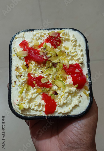 Hand holding sweet dish topped with dry fruit and cherry, food background, dessert photography, dairy ice-cream