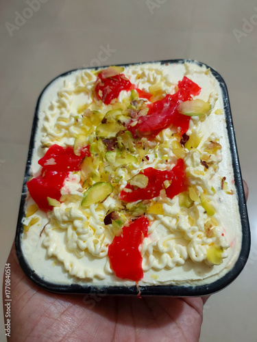 Hand holding sweet dish topped with dry fruit and cherry, food background, dessert photography, dairy ice-cream