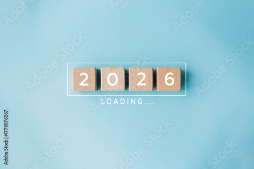 2026 loading concept with wooden cubes on blue background. Concept of new year arrival, anticipation, future plans, and transition from 2025 to 2026.
