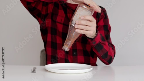 A man tries to pour ketchup from an empty bottle