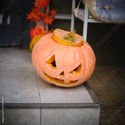 A carved Jack-o'-lantern on the street outside a cafe. Photo processed with a vignette around the edges. Happy Halloween.