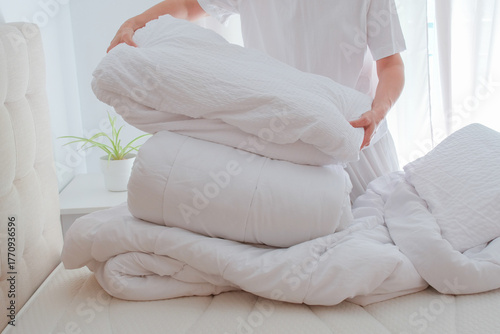 Woman changing bedding with duvets and pillows on bed in bedroom, seasonal home care, bedding washing, cleaning and care