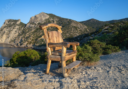 Wooden chair on the Golitsyn Trail cliff with a view of the mountain and sea, Crimea