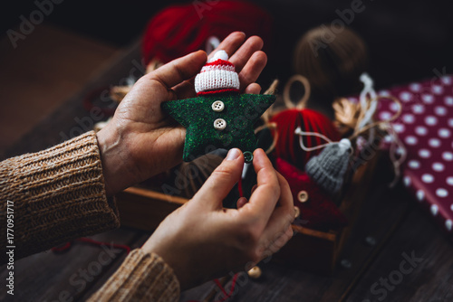 Young woman holding wooden box with artisan handmade Christmas toys. Simple DIY decorations for fir tree, holiday creative design. Leisure time with kids, art and craft. Recycled or natural materials