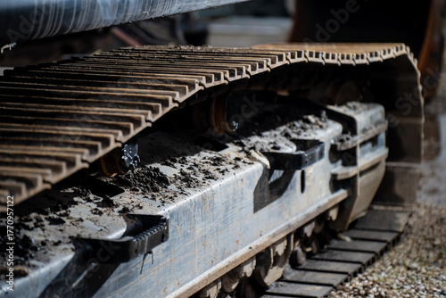 Detailed excavator steel crawler track with visible rollers and mud deposits showing advanced traction engineering, load distribution, and industrial durability in construction machinery