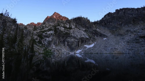 Timelapse of sunset over Trail Creek Lake in Idaho’s Sawtooth Mountains. Golden light warms rugged peaks as reflections shimmer on the calm alpine lake beneath a clear evening sky.