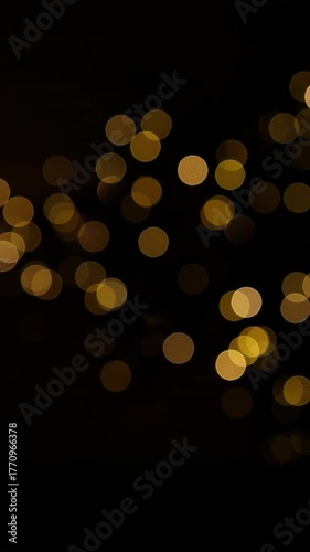 Soft golden bokeh lights on dark background. Elegant festive abstract backdrop perfect for Christmas, New Year, wedding, celebration, and luxury event videos or designs.