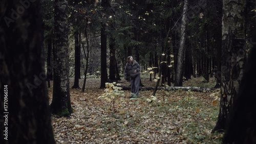 Woman running through dark forest and stopping to look back in fear