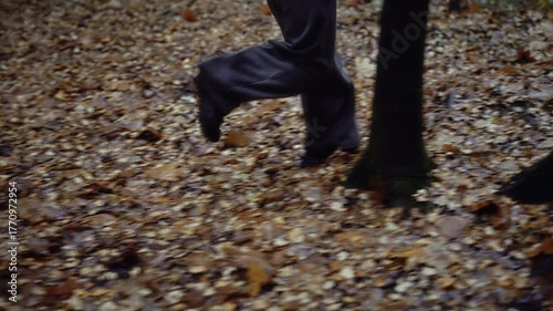 Close-up of woman running through dark autumn forest