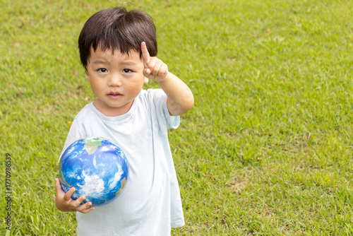 地球儀を持って草原で立っている男の子（2歳、日本人、笑顔）