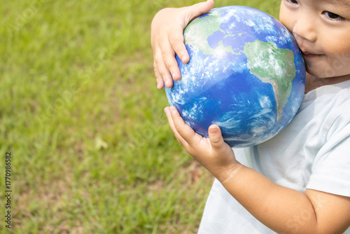 地球儀を持って草原で立っている男の子（2歳、日本人、笑顔）