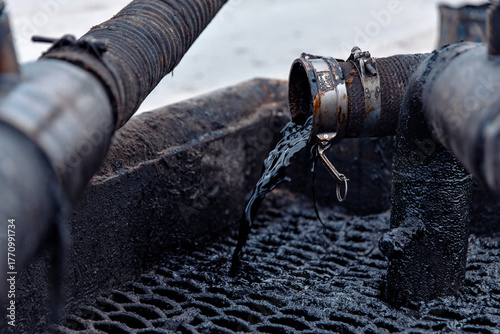 close up of crude oil flowing out of a hose. Oil field, industry and manufacturing, oil and gas production