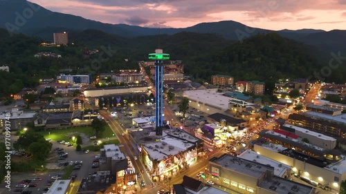 Gatlinburg, Tennessee at night with illuminated Parkway street lined with restaurants, attractions and retail shops for visitors. Forested Appalachian hills surrounding American vacation town.