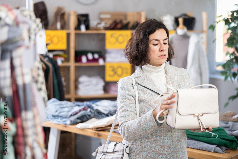 Fototapeta premium Latin American woman at trading floor pick out and buying handbag. Off line clothing store from retailer. Style and fashion look, modern trends. Discount holiday season, promotional offers.