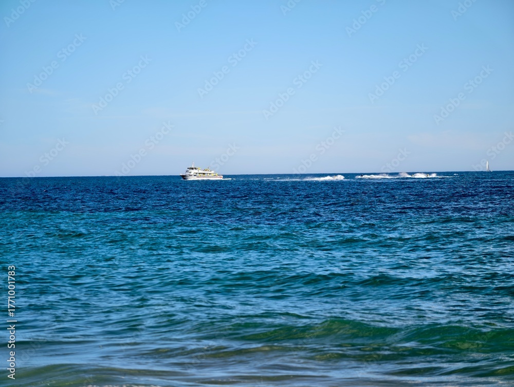 Obraz premium vast sea scene, extensive maritime landscape with faroff vessel and tranquil waves rolling in