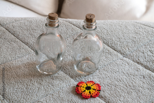 Two small glass bottles with corks and a beaded flower decoration