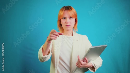 Determined businesswoman pointing finger holding laptop at you