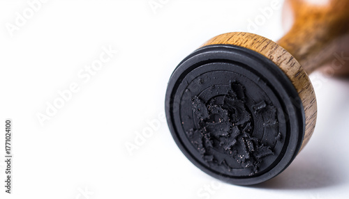A detailed macro view of a classic wooden handle rubber stamp isolated on a white background