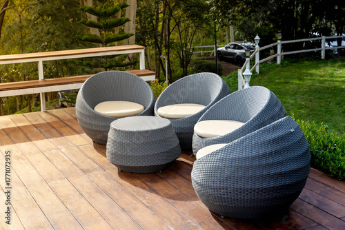 Modern outdoor patio furniture set with round wicker chairs and table on wooden deck. Perfect for resort interiors, garden design, outdoor living, hospitality spaces, and cozy relaxation concepts.