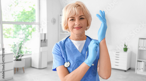 Female doctor putting on medical gloves at hospital