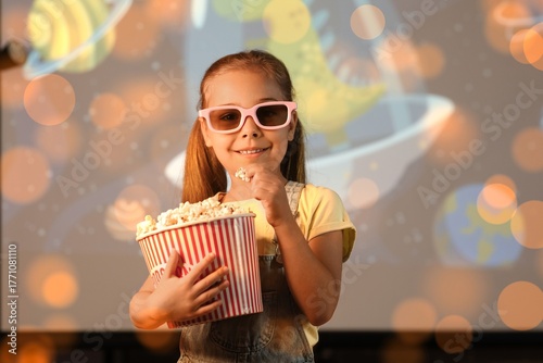 Happy girl in 3d glasses, with popcorn and cartoons on projector screen at home