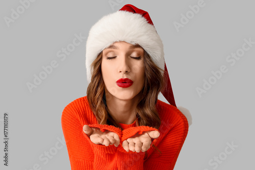 Young woman in Santa hat bl...