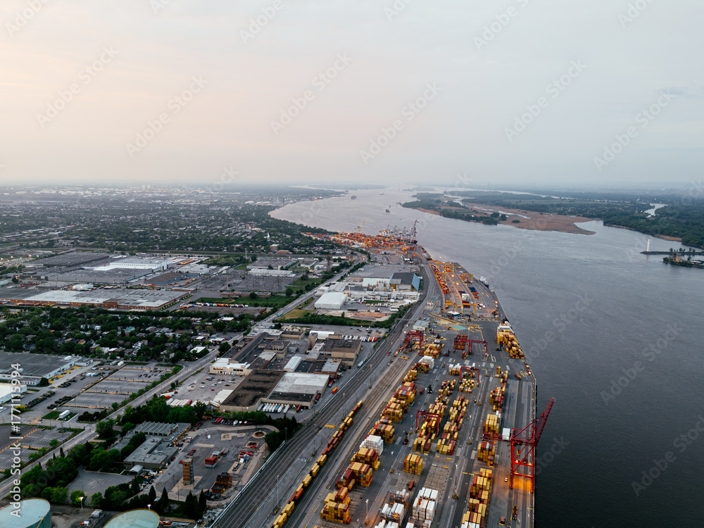 Fototapeta premium Aerial view of Montreal port with cargo containers, cranes and city skyline at sunset. g.
