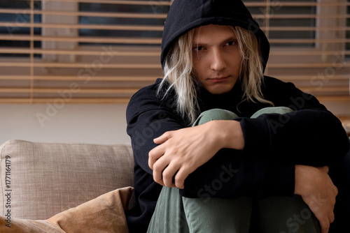 Sad young man sitting on so...