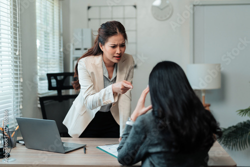 Fototapeta Asian female boss yelling and pointing finger at upset employee during workplace