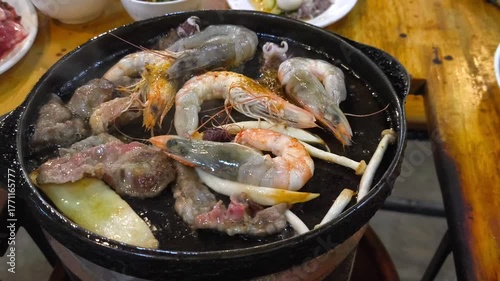 Close-up fresh seafood and meat grilling on a hot pan with mushrooms in BBQ buffet restaurant