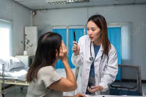 Wallpaper Mural Female doctor in white coat examining patient's eyes with a penlight during a medical check up in a hospital room Torontodigital.ca