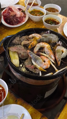 Close-up fresh seafood and meat grilling on a hot pan with mushrooms in BBQ buffet restaurant