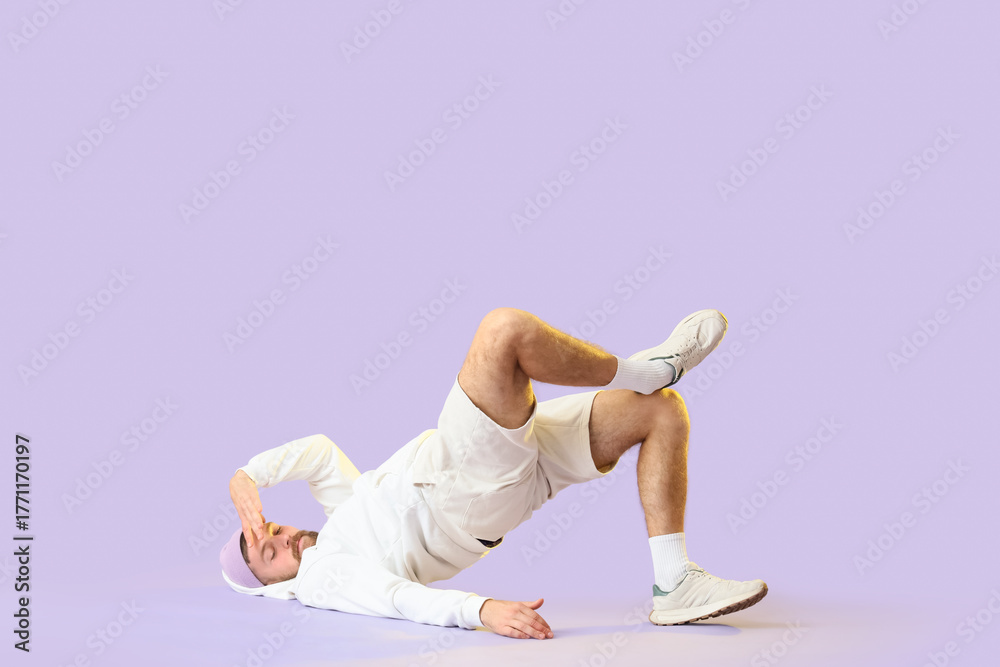 Naklejka premium Handsome young man dancing hip-hop on lilac background