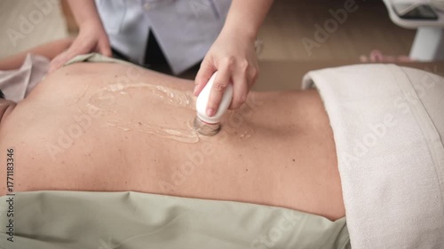 Closeup shot, male Asian patient is recovery treated, gel ultrasound for back pain relief by female physical muscle doctor, passive medical therapy at spa clinic, and wellness massaging healthcare.