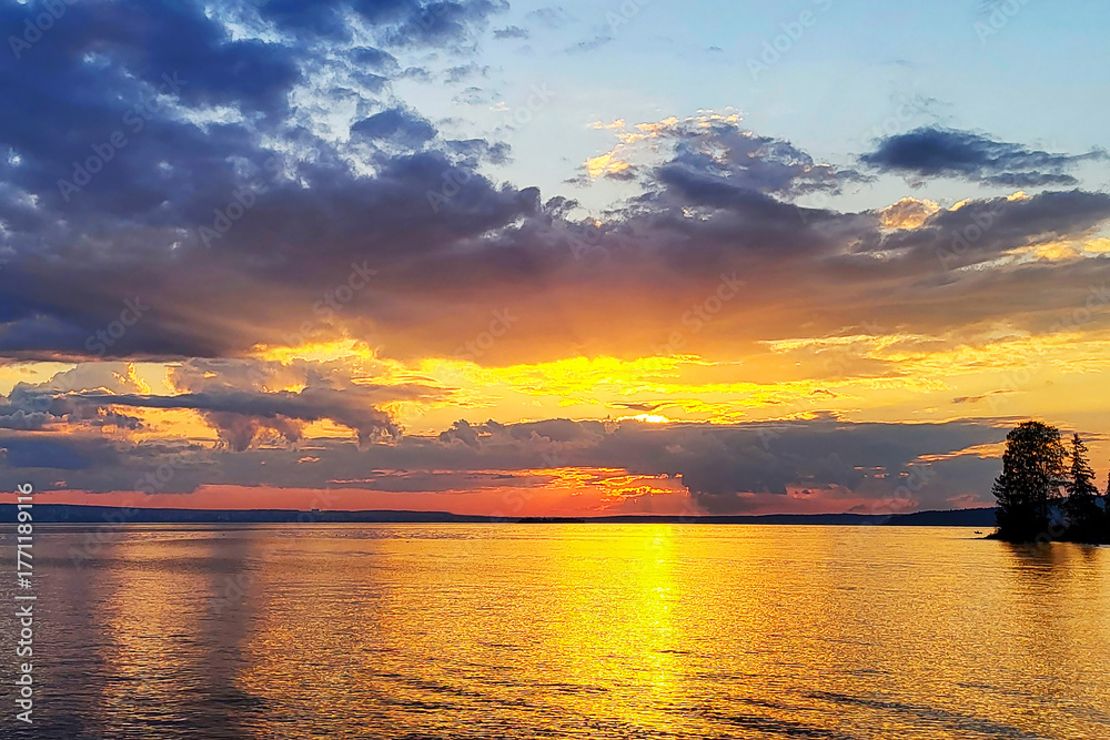Obraz premium Evening autumn landscape of the sunset over the horizon against the backdrop of the waters of a large lake.