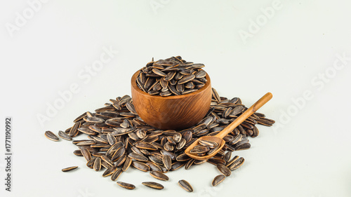 Kuaci or Kwatji is a typical Indonesian snack consisting of dried and salted sunflower seeds in a wooden bowl on a white background.