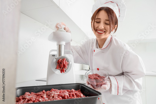 Female chef using meat grin...