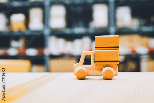 Wooden toy truck carrying cardboard boxes in warehouse represents logistics, delivery service, e-commerce shipping, transportation, inventory management, and supply chain business concept.