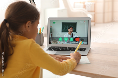 Little girl studying Math with online tutor at home, back view