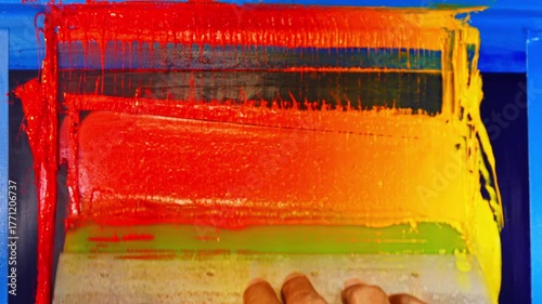 The screen printing process captured in detail as bright inks transition from yellow to deep red across the mesh, emphasizing the skill and precision required to craft a stunning handcrafted print.