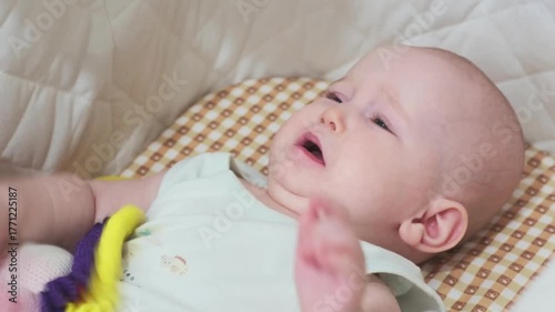  baby girl is lying on the bed and crying. The kid touches her legs.